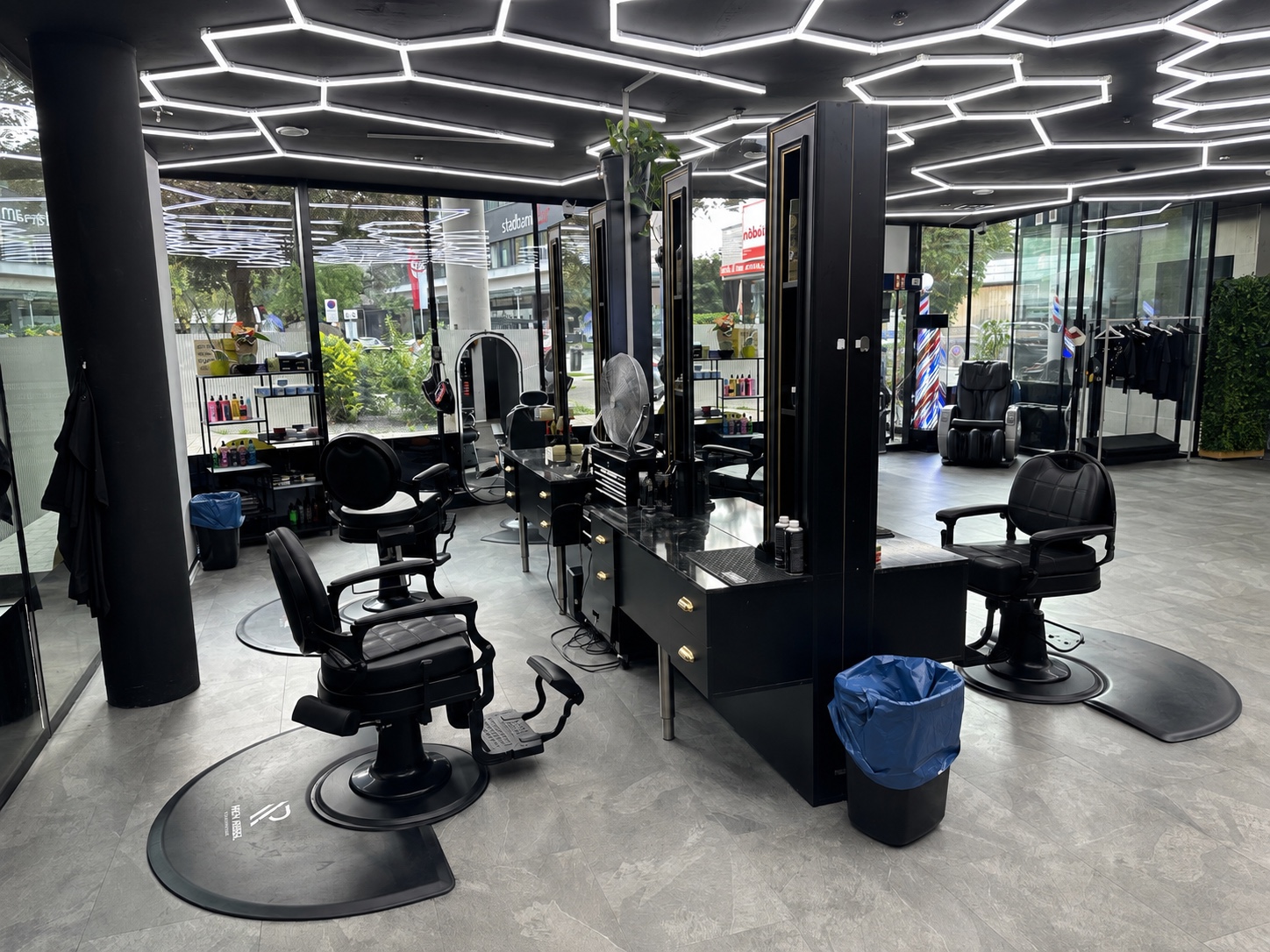 Innenraum von MAX Herrenfriseur in Wörgl mit schwarzen Friseurstühlen und sechseckiger LED-Deckenbeleuchtung